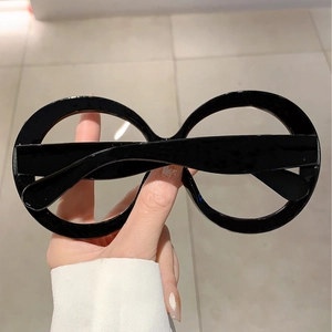 Detail of oversized black round frames with thick glossy finish and blue light blocking lenses