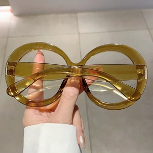 Detail of oversized amber round frame glasses held by hand showing retro style and texture