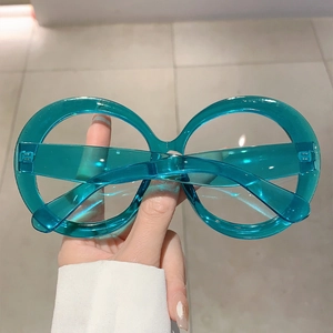 Detail shot of oversized round eyeglasses in translucent teal resin material