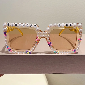 Close-up of pearl-studded square sunglasses featuring Birthday Girl beaded lettering