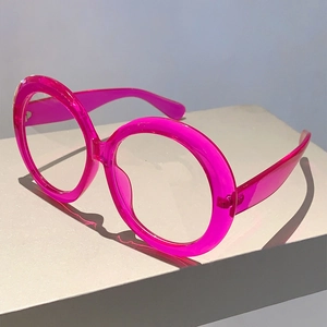 Detail of oversized round glasses in transparent pink with thick frames on display
