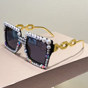 Detail of square sunglasses with pearls and Birthday Girl lettering on gold chain arms