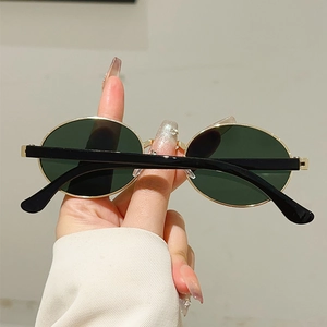 Close-up of vintage oval metal sunglasses with golden frame and dark lenses