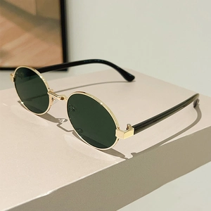 Detail view of oval retro sunglasses with gold metal frame on a beige pedestal