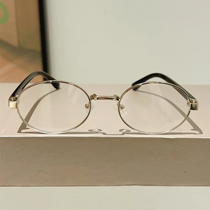 Detail of vintage metal oval glasses frame with slim gold wire and black temples