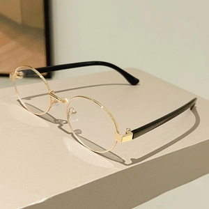 Detail view of oval metal frames and black temples on minimalist fashion sunglasses