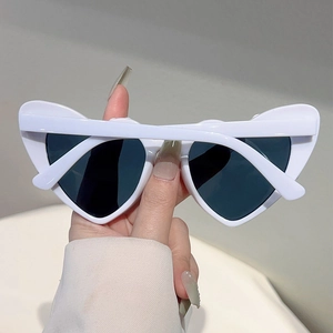 Close-up of white heart-shaped sunglasses with dark lenses for bride-to-be party style