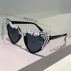 Detailed view of heart-shaped Bride To Be sunglasses with rhinestones and size dimensions