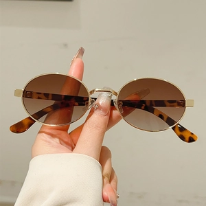Retro metal oval sunglasses with gold frame and gradient brown lenses in hand