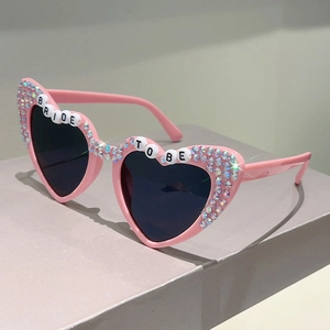 Close-up of pink heart sunglasses with BRIDE TO BE lettering and sparkling rhinestones
