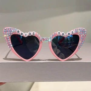 Detail of pink heart-shaped sunglasses with BRIDE TO BE text and sparkling rhinestones