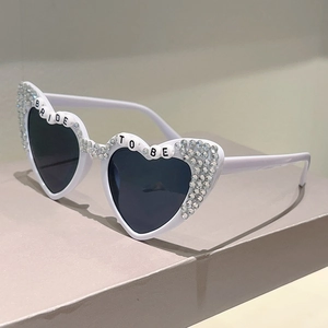 Close-up of BRIDE TO BE heart sunglasses with white frames and rhinestone crystal accents
