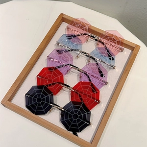 Detail of five colorful rimless spider web sunglasses arranged in a wooden tray