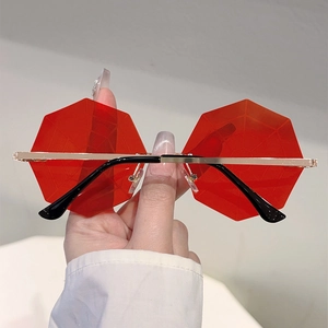 Close-up of red octagonal rimless sunglasses with gold metal frame and clear red lenses