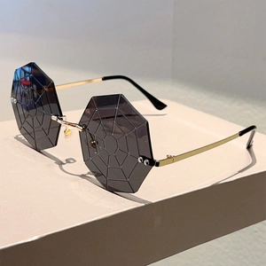 Detail of rimless octagonal sunglasses featuring deep grey spider web engraved lenses