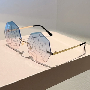 Close-up of frameless octagon sunglasses with spider web texture and blue-pink gradient lens