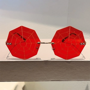Detailed view of red octagonal rimless sunglasses featuring a unique spider web lens pattern