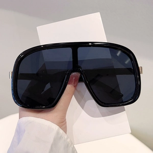 Close-up of oversized one-piece sunglasses featuring black glossy frames and silver hinges