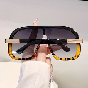 Detail of oversized sunglasses with leopard print frame and golden metal hinge
