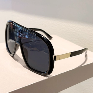 Close-up of golden metal hinge on black shield sunglasses with gray lenses
