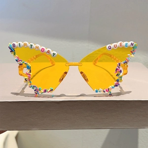 Macro detail of butterfly party sunglasses with yellow lenses and Birthday Queen beadwork