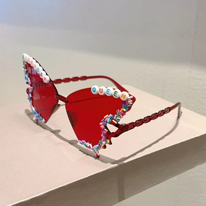 Macro detail of red butterfly party sunglasses featuring Birthday Queen bead lettering