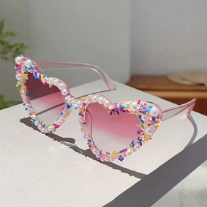 Detail der herzförmigen Sonnenbrille mit rosa Farbverlauf und perlenbesetztem Rahmen