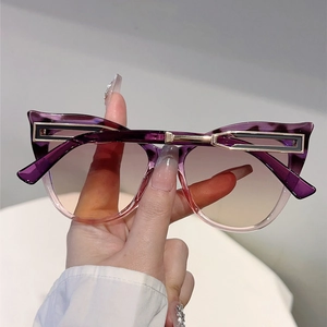 Close-up of cat-eye sunglasses featuring purple gradient frames and gold metal temple details