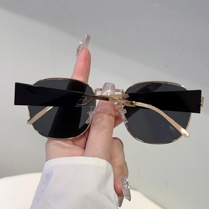Detailansicht des goldenen Metallrahmens und der dunklen ovalen Gläser der Sonnenbrille