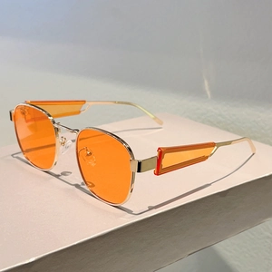 Nahaufnahme der goldenen Oval-Sonnenbrille mit orangefarbenen Gläsern und Metalldetails
