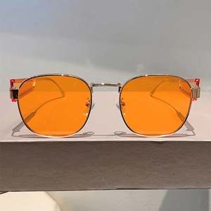 Detailansicht der goldenen Metall-Sonnenbrille mit auffällig orangefarbenen Gläsern