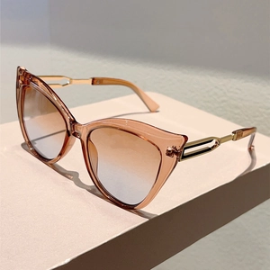 Detail of cat-eye sunglasses with amber frames and gold hollowed-out metal temples