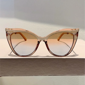 Detail view of cat-eye sunglasses with dual-tone gradient lenses and amber frames