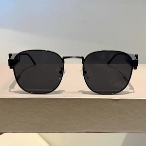 Detailansicht der schwarzen Metall-Sonnenbrille auf einem minimalistischen Ständer