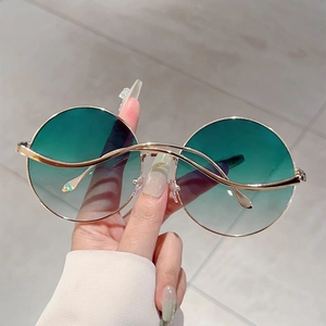 Detailed macro view of gold wavy bridge design and gradient lenses on round sunglasses