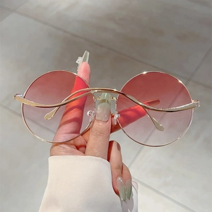Detail of round sunglasses with pink gradient lenses and gold metallic frame