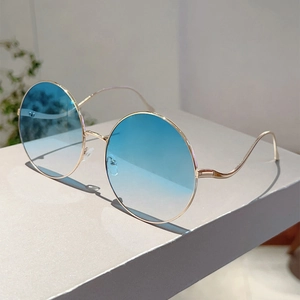 Detail of round metal sunglasses with gold frame, blue gradient lenses and wavy temples