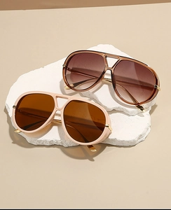 Detail of two pilot sunglasses in beige and tortoiseshell finish on a white stone base