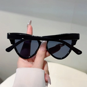Close-up of black oversized cat-eye sunglasses with wide temples and dark grey lenses