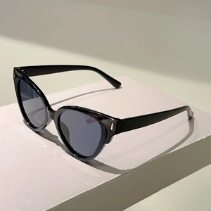 Detail view of modern black cat-eye sunglasses with dark grey lenses on grey pedestal