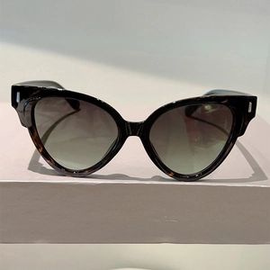 Detail of cat-eye sunglasses featuring black frames with tortoise accents and gradient lenses