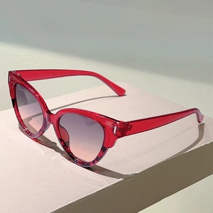 Macro detail of red transparent cat-eye sunglasses with gradient lenses and silver accents