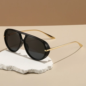 Oversized black pilot sunglasses with gold metal temples and double bridge on white stone