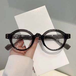 Close-up of translucent grey round eyeglass frames with silver rivet detail