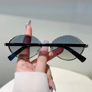 Close-up of oval silver metal sunglasses with blue-yellow gradient lenses and black temples