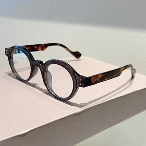Macro detail of retro round frame glasses with brown finish and tortoiseshell patterned temple