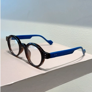 Detail view of round vintage glasses with tortoise frame and blue temples on stand