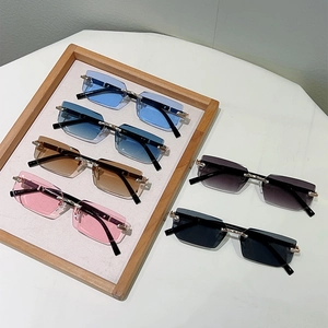 Flat lay of rimless square sunglasses in blue, tea, and pink with gold metal temples