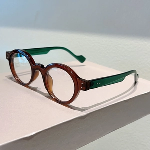 Detail of round tortoiseshell glasses frames with transparent green temple and metal rivets