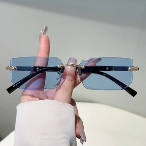 Detail of rimless rectangle sunglasses with light blue lenses and gold metal nose bridge